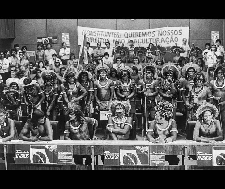 À frente na bancada, da esquerda para a direita: Teseya Panará, Kanhõc Kayapó, Raoni Mētyktire e Tutu Pombo Kayapó, dentre outros, ocupam auditório da liderança do PMDB nas negociações do capítulo dos indígenas na Constituinte, Brasília, 31.05.1988