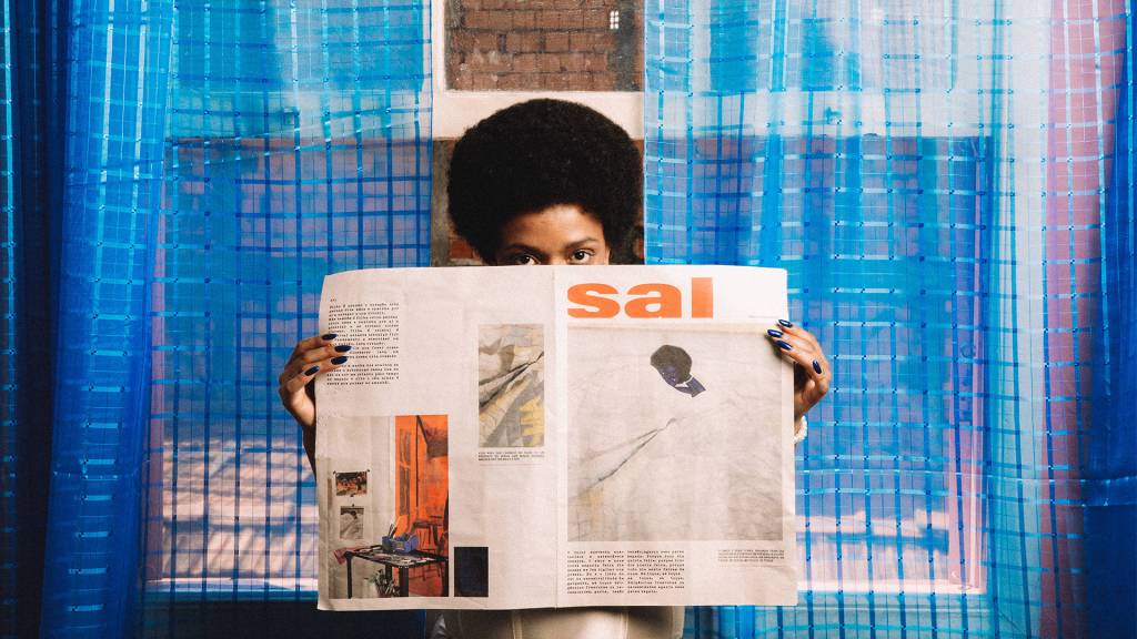 anelis-1 Anelis segura um jornal, em uma das páginas está a capa do seu álbum mais recente, Sal.
