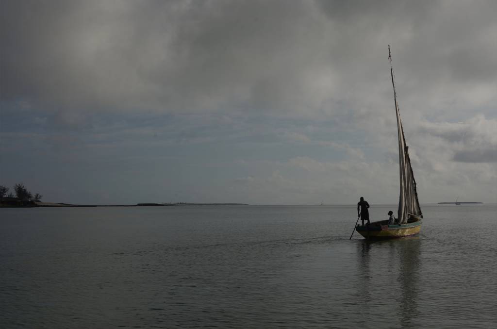 05-barconamadrugada Foto do horizonte, na foto mas e céu com muitas nuvens, a direita é possível ver um barco com pessoas dentro.